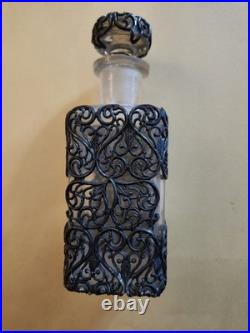 This Vintage French perfume bottle a clear glass body encased In Metal Overlay