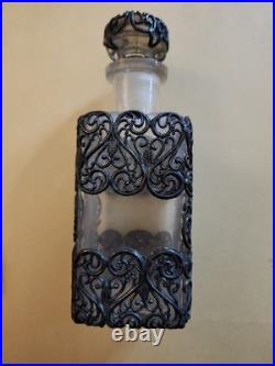 This Vintage French perfume bottle a clear glass body encased In Metal Overlay