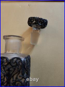 This Vintage French perfume bottle a clear glass body encased In Metal Overlay